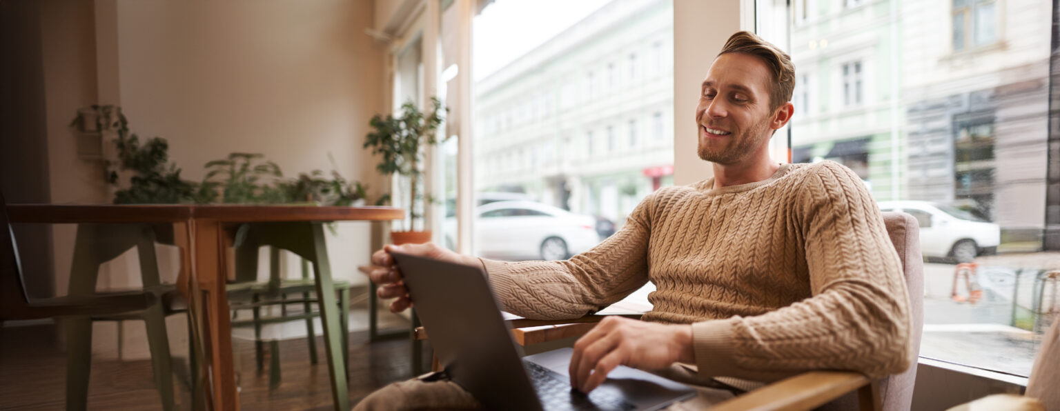 Ondernemer werkt ontspannen op zijn laptop in een café