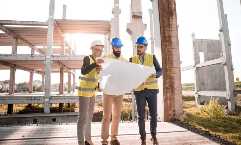 Medewerkers in de bouw bespreken een bouwtekening op de bouwplaats